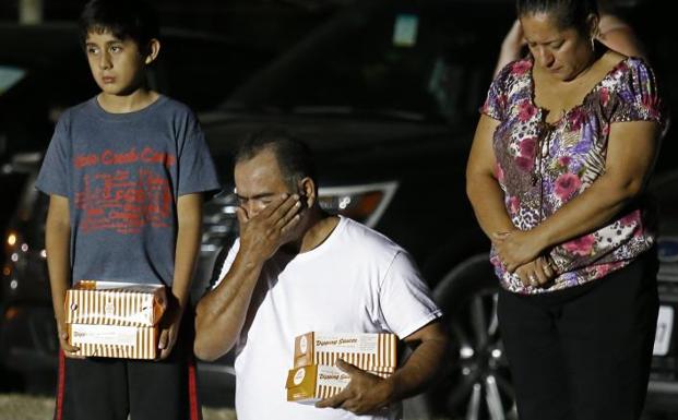 Un hombre de rodillas llora durante una vigilia en honor a los fallecidos. /Efe