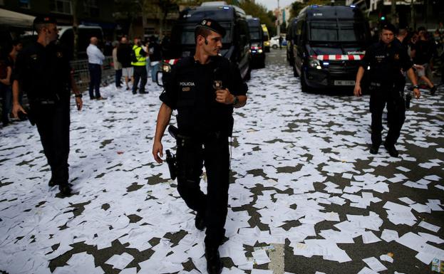 Mossos d´Esquadra andado por una calle cubierta de papeletas del referendum del 1-O. /Jon Nazca (Reuters)