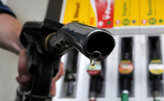 Un conductor sostiene una manguera de combustible para repostar/AFP