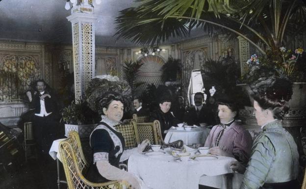 Foto coloreada a mano del salón de té en la primera clase del 'Titanic'. Al fondo, la orquesta tocando.