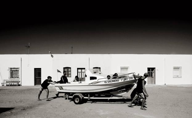 Una barca es empujada hacia el mar en el poblado de las Salinas del Cabo de Gata (Almería)./