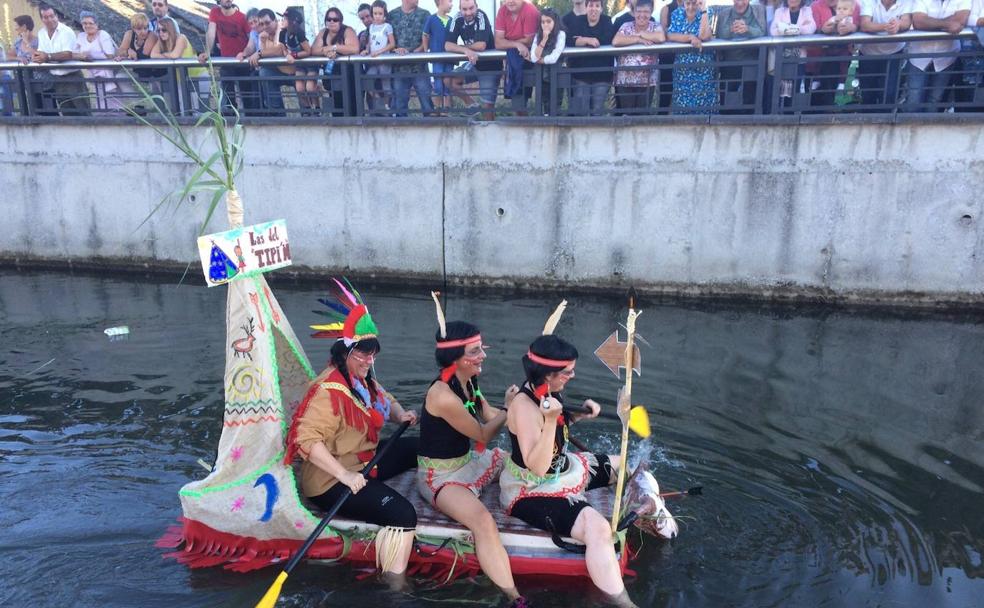 Una de las barcas con todos su tripulantes disfrazados que descienden por el río durante las fiestas de la Soledad de Camponaraya./