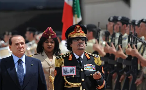 Gadafi, escoltado por una agente de su equipo de guardaespaldas, es recibido en 2008 por Berlusconi en el aeropuerto de Roma../C. SIMON / AFP